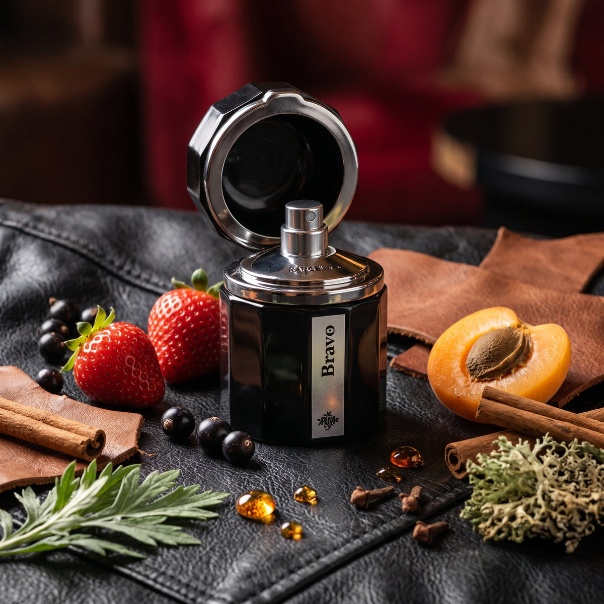Frasco octogonal negro brillante con tapón abierto tipo tintero de Bravo de Ramon Monegal, rodeado de fresas, casis, cuero, clavo de olor y musgo, estilo Casa Flores.