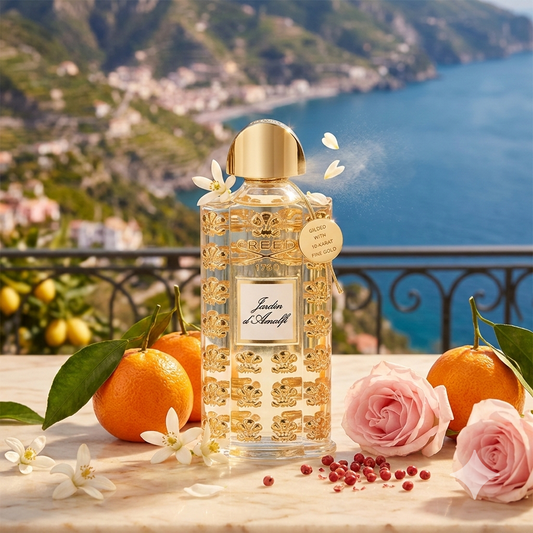 Lujoso frasco de Creed Jardin d'Amalfi con detalles dorados, rodeado de mandarinas frescas, flores de neroli y rosas frente a la hermosa Costa Amalfitana.