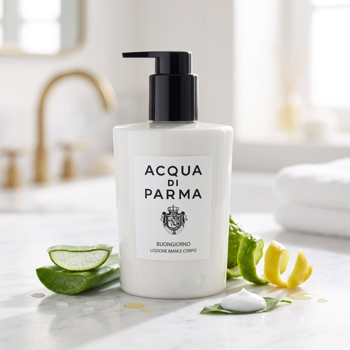Frasco blanco art déco con dosificador negro de la loción Fiordilatte Mani e Corpo Buongiorno de Acqua di Parma, rodeado de aloe vera y aceites ligeros, estilo Casa Flores.