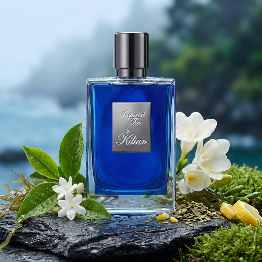 Frasco de cristal con interior azul cobalto, placa plateada y tapón oscuro de Imperial Tea de By Kilian, rodeado de hojas de té verde, jazmín, mate y algas marinas, estilo Casa Flores.
