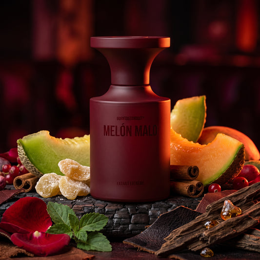Frasco rojo oscuro mate de Melón Malo de BORNTOSTANDOUT® sobre cuero negro con melón, rosa de Bulgaria y madera de oud, estilo Casa Flores.
