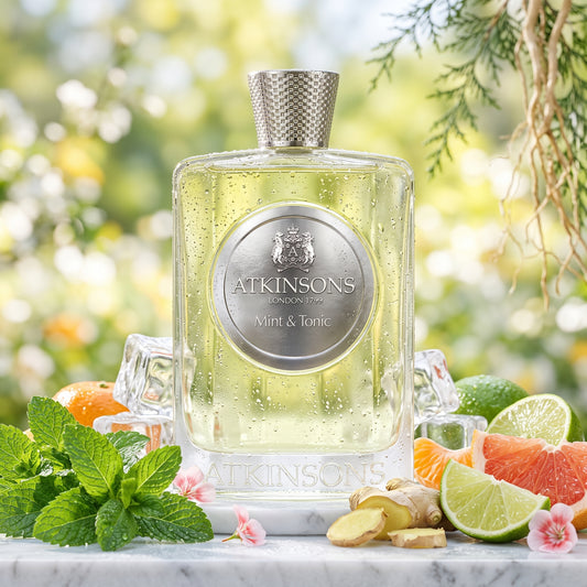 Frasco de Mint & Tonic de Atkinsons con placa circular plateada sobre barra de mármol con hielo, menta y lima, estilo Casa Flores.