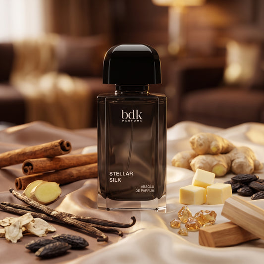 Frasco oscuro de Stellar Silk de BDK Parfums con tapón negro sobre seda con vainilla, canela y sándalo blanco, estilo Casa Flores.